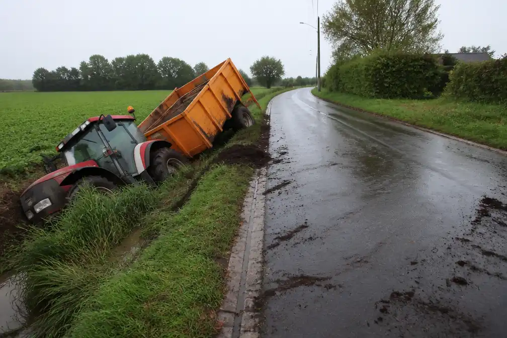 Landbouwvoertuig belandt in gracht in Bazel, wegdek honderden meters met olie besmeurd