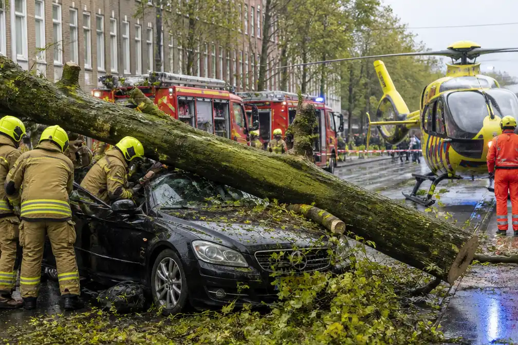 Boom valt op rijdende auto in Anne Frankstraat Amsterdam, bestuurder bekneld